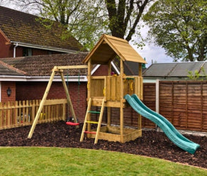 Aire de jeux en bois avec toboggan et balançoire installée dans un jardin