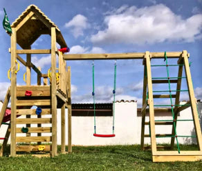Aire de jeux en bois avec balançoire, filet à grimper, échelle et toboggan dans un jardin